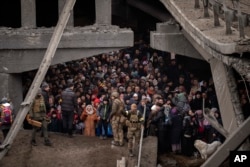 Ресей күштерінің әуе шабуылынан қауіптеніп, Киев маңындағы Ирпень қаласында құлаған көпір астына тығылып тұрған бейбіт адамдар. Украина, 5 наурыз 2022 жыл.