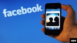 Apple iPhone 4 қалта телефоны Facebook компаниясының логотипінің фонында. Ганновер, 10 сәуір 2012 жыл