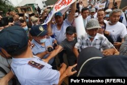 Полицейлер митинг қатысушыларынан плакатын тартып алуға тырысып жатыр. Алматы, 6 шілде 2021 жыл.