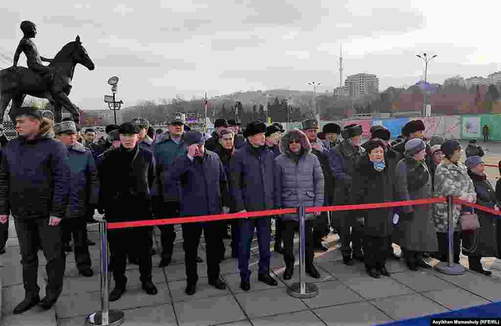 Алматы қаласының әкімі Бауыржан Байбек (ортада) бастаған шенеуніктер Тәуелсіздік ескерткішіне гүл қою рәсімінде тұр. Алматы, 16 желтоқсан 2018 жыл.